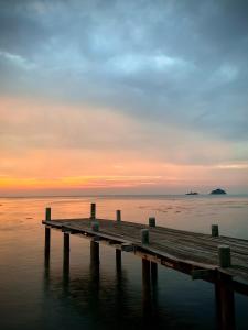 a wooden dock in the water at sunset at Kaibae Hut Resort in Ko Chang