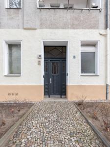 eine schwarze Tür in einem Gebäude mit zwei Fenstern in der Unterkunft Apartments Berlin Aroser Allee in Berlin