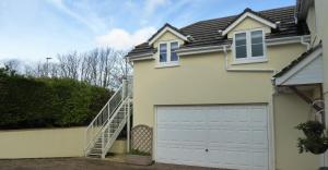 een wit huis met een garagedeur en een trap bij The Captains Quarters, Woolsery in Bideford