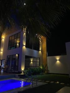 a house with a palm tree and a swimming pool at night at فيلا بلاتنيوم اند كي ام in Unayzah