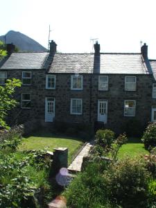 una antigua casa de piedra con un jardín delante de ella en Pen Llyn Quarryman's Cottage, en Trevor