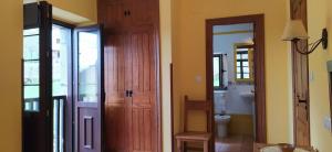 a bathroom with a wooden door and a toilet at La Corona del Auteiro in Valle de Lago +77 photos