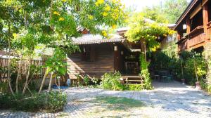 a wooden house with a tree and a patio at Lampang Lanna Home in Lampang