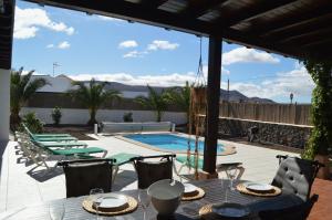 ラ・オリーバにあるVilla spacieuse et lumineuse avec piscine Chaufféeのパティオ(テーブル、椅子付)、スイミングプールが備わります。