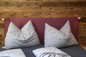 two pillows on a bed with a purple headboard at M4 Appartements in Wagrain