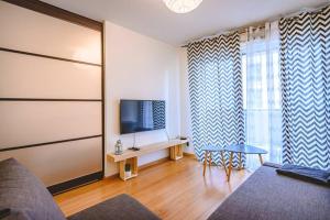 uma sala de estar com um sofá, uma televisão e uma mesa em CAMILLE - Appartement avec extérieur em Reims