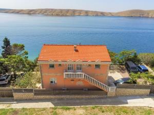 a house with an orange roof next to the water at Apartments Horvat on Island Pag in Vlašići