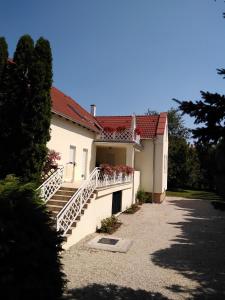 une maison blanche avec des escaliers et des fleurs. dans l'établissement Boglárka Apartmanház, à Balatonfüred