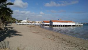 a beach with a pier and a building in the water at BALNEARIO LA ENCARNACIÓN in Los Alcázares