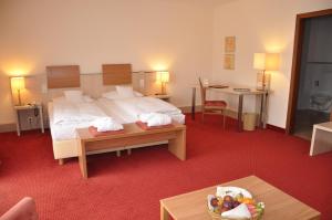 バート・ヘルスフェルトにあるHotel am Kurparkのベッドとテーブルが備わるホテルルームです。
