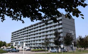 un gran edificio con coches estacionados en un estacionamiento en City hotel Terneuzen, en Terneuzen