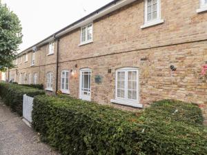 a brick building with white windows and a hedge at Swallow Cottage in Herne Bay