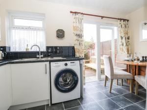 a kitchen with a washing machine and a table at Jay Cottage in Weymouth