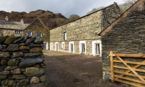 a row of stone buildings with a wooden gate at Kentmere Hall Bank Barn in Kentmere