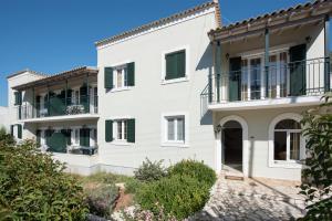 a large white house with green shutters at Balaris Apartments in Kassiopi