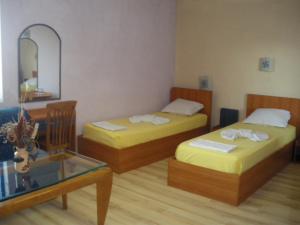 Habitación con 2 camas, mesa y espejo. en Brani Family Hotel, en Ruse