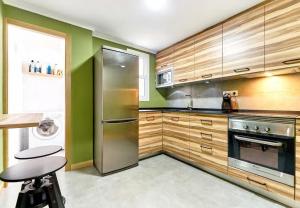 cocina con armarios de madera y nevera de acero inoxidable en Apartamento Morales - 2 habitaciones, espacioso y tranquilo junto a Hospital, en Murcia