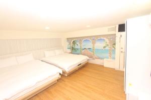 a bedroom with two beds and a painting on the wall at Sea Keelung in Keelung