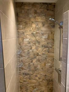 a shower with a stone wall in a bathroom at Huisje Koolmees park Hoefbos Otterlo in Otterlo