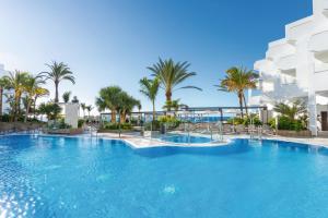 a large swimming pool in a tropical setting at Hotel Riu Palace Jandia in Playa Jandia