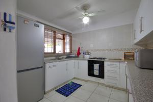 cocina con electrodomésticos blancos y ventilador de techo en St. Lucia Ocean View Holiday Home en St Lucia