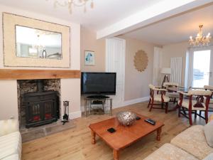 Una sala de estar con chimenea y televisión. en Blue Buoy Cottage, en Brixham