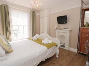 1 dormitorio con cama blanca y lámpara de araña en Blue Buoy Cottage, en Brixham