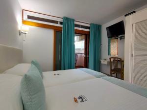 a bedroom with a white bed with blue curtains at Apartamentos El Paseo in Playa del Ingles