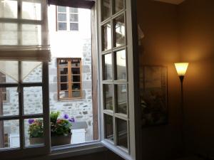 a window in a room with flowers and a lamp at L'Oustal du Sentier in Mur-de-Barrez