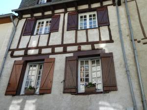 un edificio con ventanas de madera con contraventanas y flores. en L'Oustal du Sentier, en Mur-de-Barrez