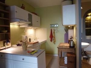 a kitchen with green walls and white cabinets at L'Oustal du Sentier in Mur-de-Barrez