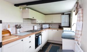 een keuken met witte kasten en een fornuis met oven bij Sunbeam Cottage in Coniston