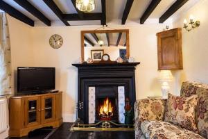 een woonkamer met een open haard en een televisie bij Sunbeam Cottage in Coniston