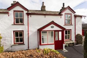 Sunbeam Cottage في كونيستون: منزل أبيض مع باب احمر