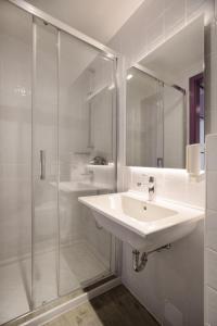 a white bathroom with a sink and a shower at Hostel Link in Lovran