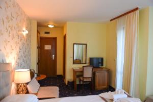 バンスコにあるFamily Hotel Lazurのベッド、デスク、テレビが備わるホテルルームです。
