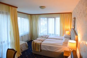 pokój hotelowy z dużym łóżkiem i oknami w obiekcie Family Hotel Lazur w mieście Bansko