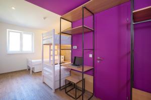 a room with purple walls and a desk with a laptop at Hostel Link in Lovran