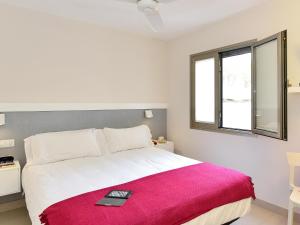 a bedroom with a large white bed with a red blanket at San Agustin Beach Apartments in San Agustin