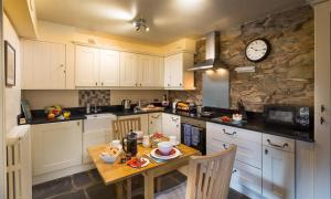 cocina con mesa y reloj en la pared en Riverbank At Stepping Stones, en Ambleside