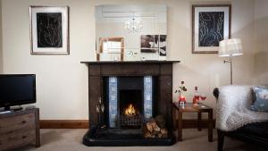 a living room with a fireplace and a tv at Riverbank At Stepping Stones in Ambleside