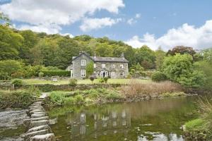 an old house with a river in front of it at Riverbank At Stepping Stones in Ambleside