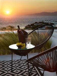 een tafel en stoelen met wijnglazen en de zonsondergang bij Epic Mykonos in Mykonos-stad