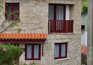 un edificio in pietra con finestre rosse e balcone di Casas Da Ribeira a Seia