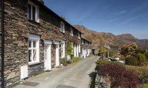 a row of houses on a street with mountains in the background at Dormouse Cottage in Coniston
