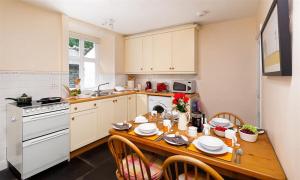 a kitchen with a wooden table with plates on it at Dormouse Cottage in Coniston