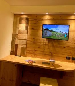 um quarto com uma parede com uma televisão numa parede de madeira em Hotel Laurino em Pozza di Fassa