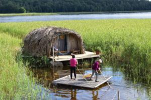 two people on a dock in the water with a boat at Bebru māja - Beaver house in Usma