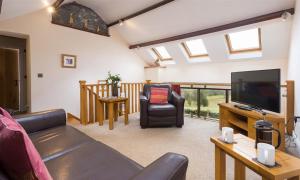 ein Wohnzimmer mit einem Sofa und einem TV in der Unterkunft Nest Barn in Keswick