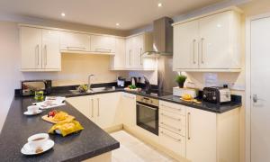 a kitchen with white cabinets and a black counter top at Lakeland Loft in Windermere +2 photos